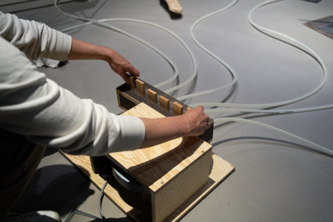 Person betätigt die Installation indem sie Holzplättchen verschiebt die in einem Kasten gesteckt sind und Töne produzieren.