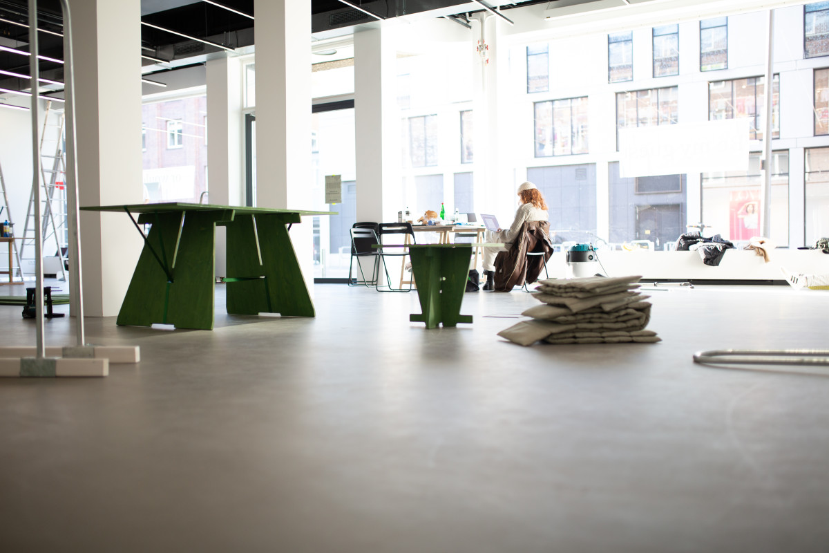 Aufbausituation im noch fast leeren spce | Muthesius, mit Person in Rückenansicht am Laptop