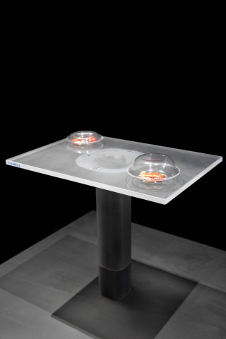 Modellbau mit zwei Cut-Out Personen aus Glas vor einem beleuchteten Tisch