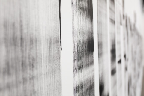 Schwarze Flächen mit Pinselstrukturen auf einer weißen Wand.