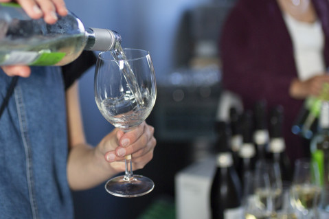 Frau befüllt ein Glas Wein.