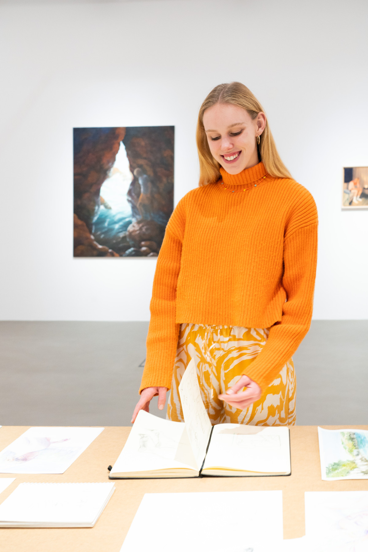 A picture of the artist Janna Schnoor in front of her painting 